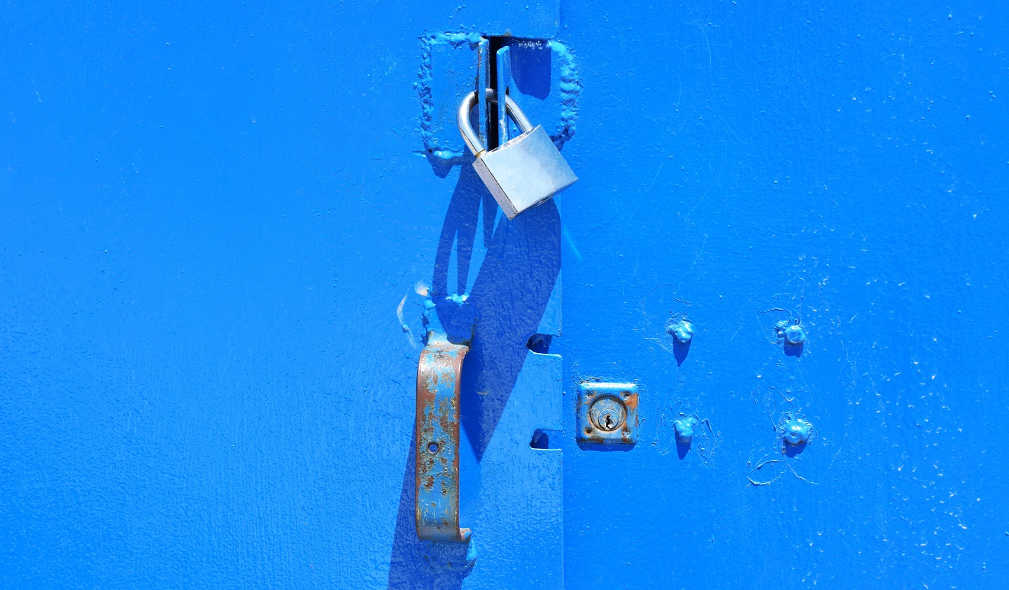 An image of a padlock being used to secure a blue metal door