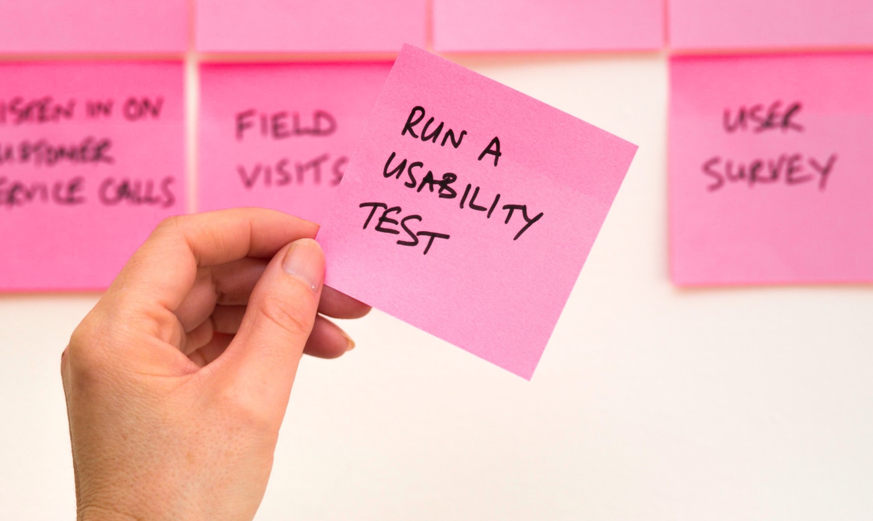 A hand holding a note making reference to running a usability test